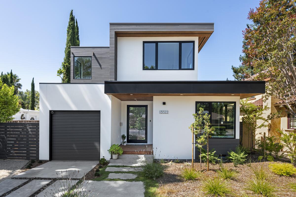 A prefabricated white house in Palo Alto with a dark grey garage door, roof, and gate made by PlantPrefab.