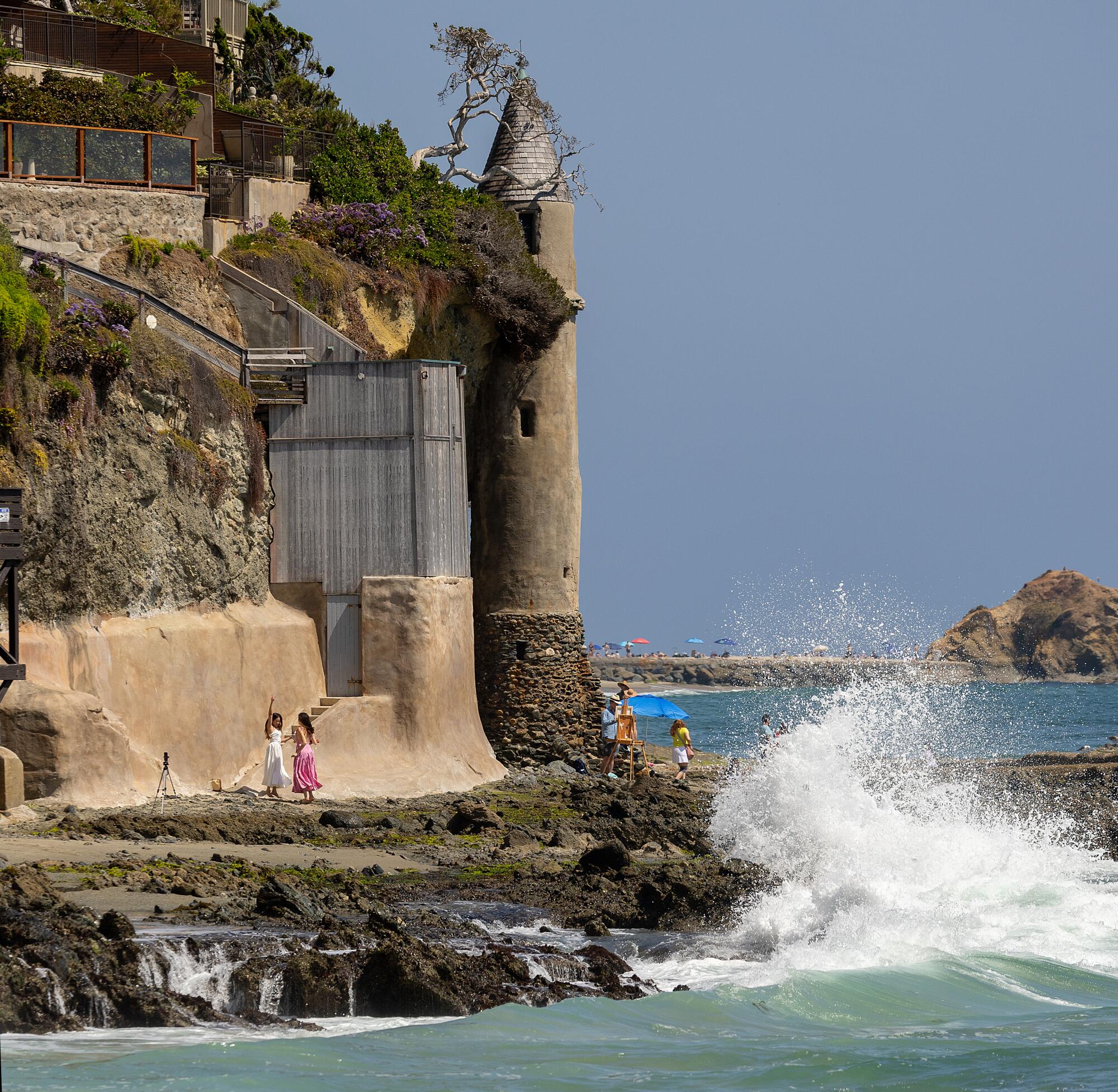 A couple dance while filming a social media video as others explore the Victoria Beach Pirate Tower in Laguna Beach.