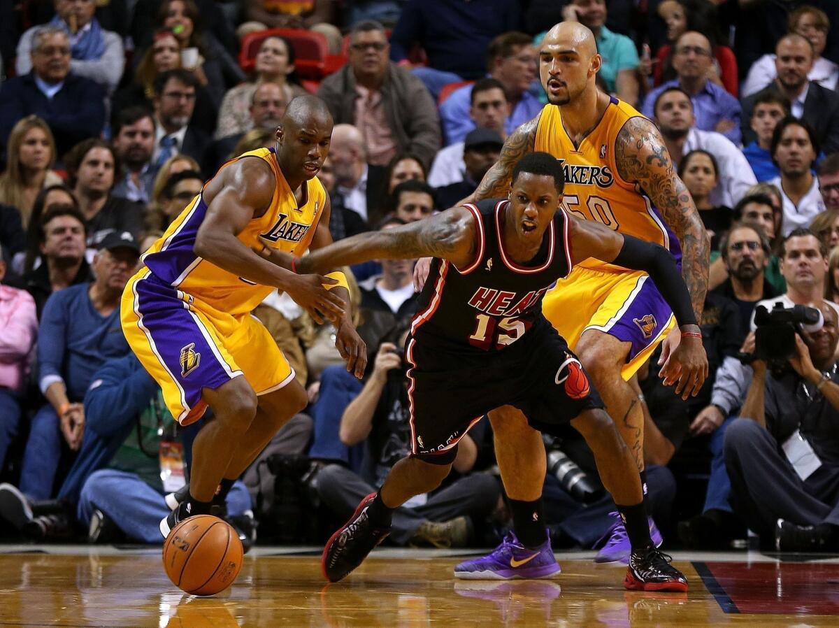 Miami guard Mario Chalmers breaks for a loose ball with Jodie Meeks during the first half of the Lakers' Thursday matchup with the Heat at American Airlines Arena.