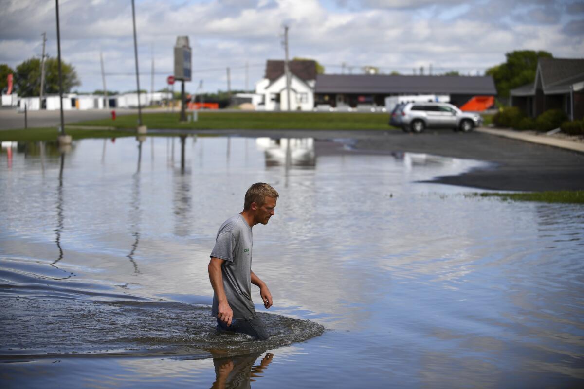 In this 2016 file photo, Chad Koosman, of Willmar, Minn., wades through flood water. As global temperatures warm, Minnesotans need to prepare for increases in catastrophic "mega-rains."