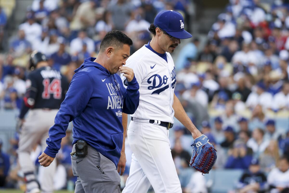 Dodgers pitcher Joe Kelly walks off the field with a trainer after experiencing tightness in his throwing arm.
