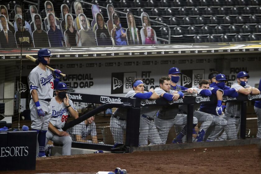Members of the Los Angeles Dodgers watch from the top step of the dugout while trailing the San Diego Padres in the ninth inning of a baseball game, Monday, Sept. 14, 2020, in San Diego. (AP Photo/Derrick Tuskan)