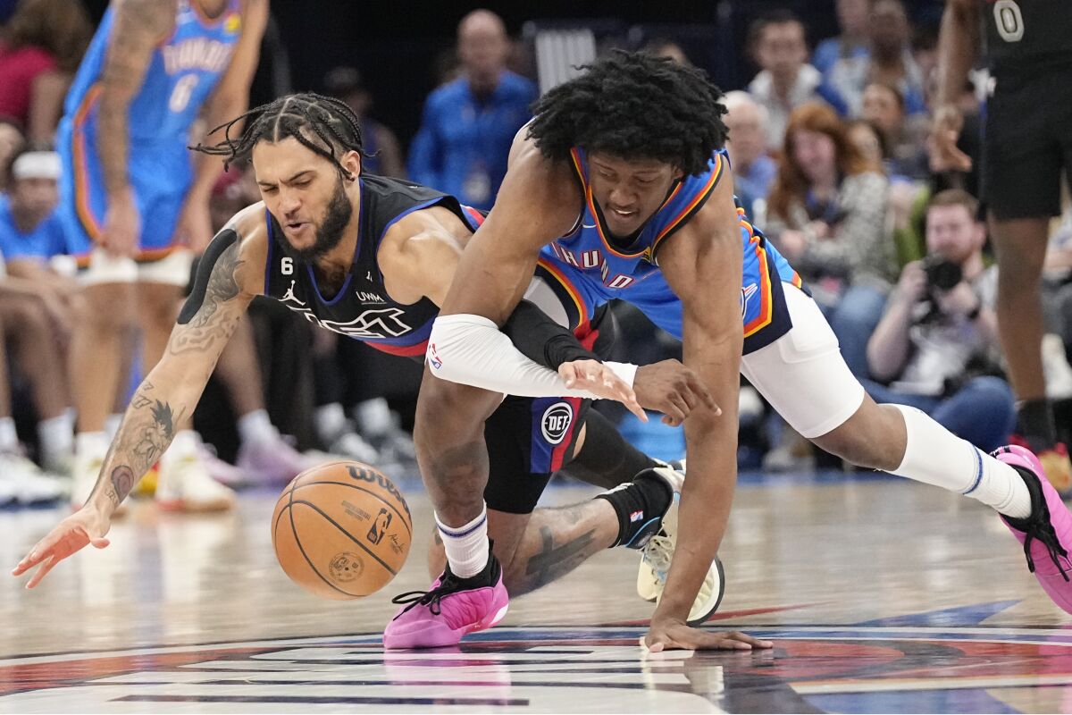 Detroit Pistons forward Isaiah Livers, left, and Oklahoma City Thunder forward Jalen Williams, right, dive for a loose ball in the first half of an NBA basketball game Wednesday, March 29, 2023, in Oklahoma City. (AP Photo/Sue Ogrocki)