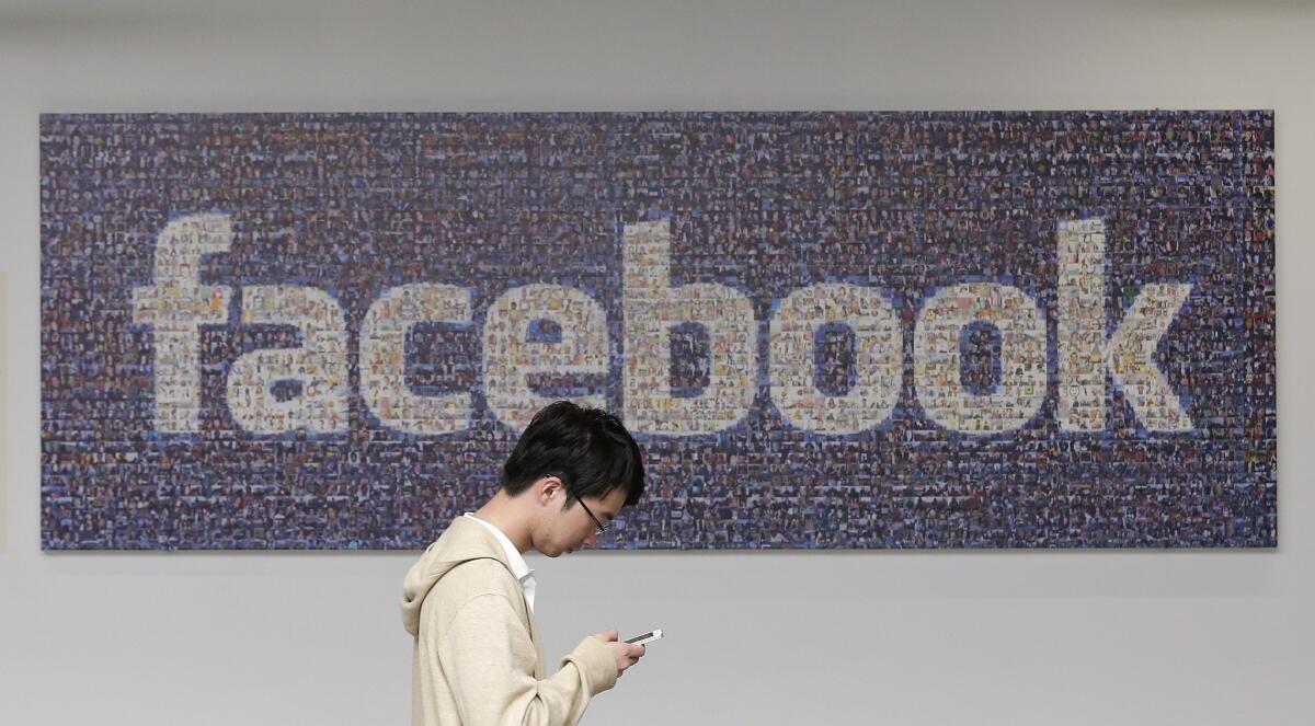 A man walks past a Facebook sign on the social media company's campus in Menlo Park, Calif. More than 26 million Facebook profile photos have taken on a rainbow hue in the days since the U.S. Supreme Court ruled that marriage is a right guaranteed under the Constitution regardless of a person's sexual orientation.