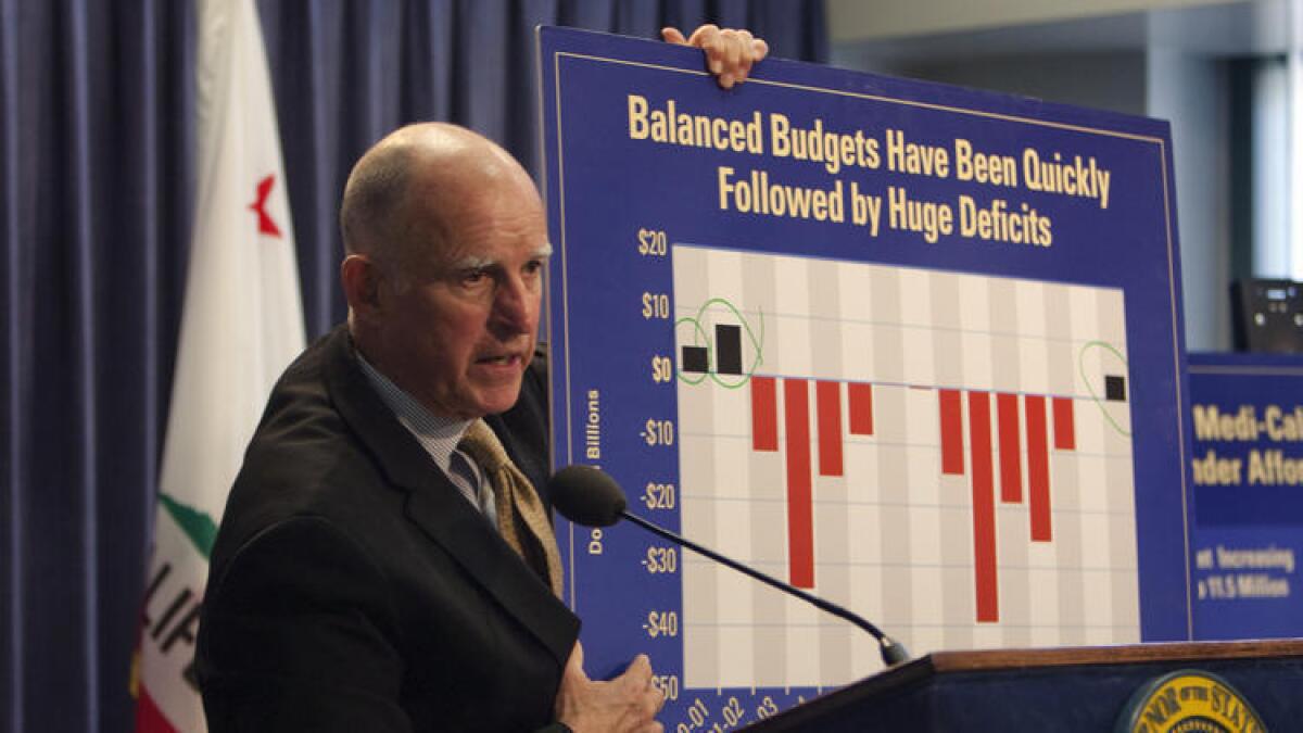 Gov. Jerry Brown holds a chart last week showing how California's finances have fluctuated between surpluses and deep deficits. A new poll shows support for Brown's budget proposals for next fiscal year.
