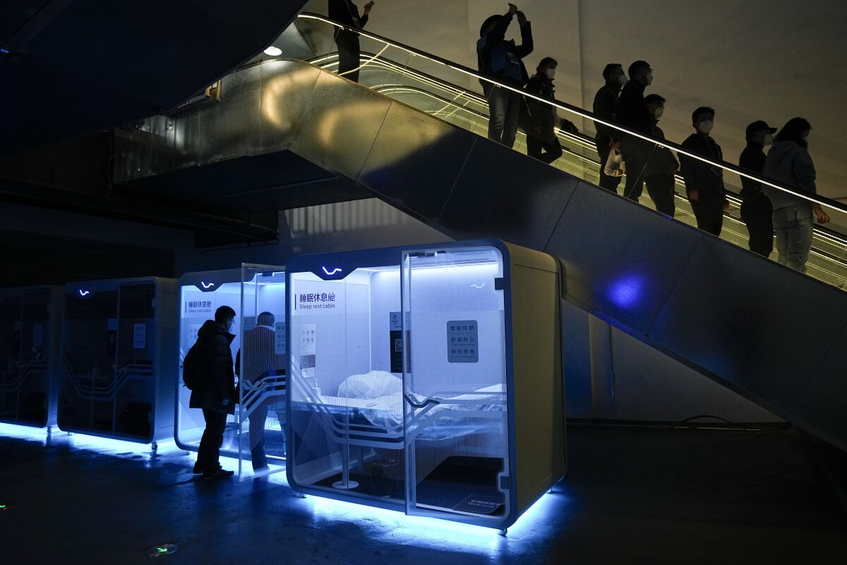 Two men walk into a sleeping pod at the main media center ahead of the 2022 Winter Olympics, Wednesday, Feb. 2, 2022, in Beijing. (AP Photo/Jae C. Hong)