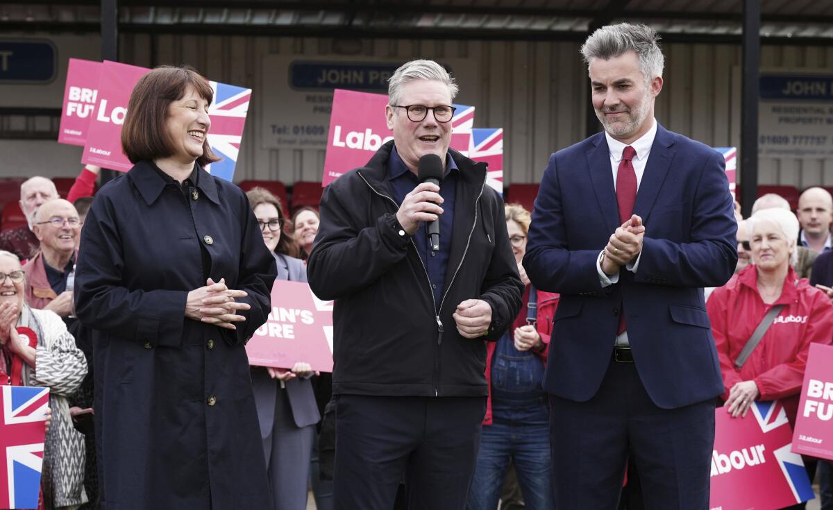 Labor Party figures, from left, Rachel Reeves, Keir Starmer and David Skaith celebrate onstage