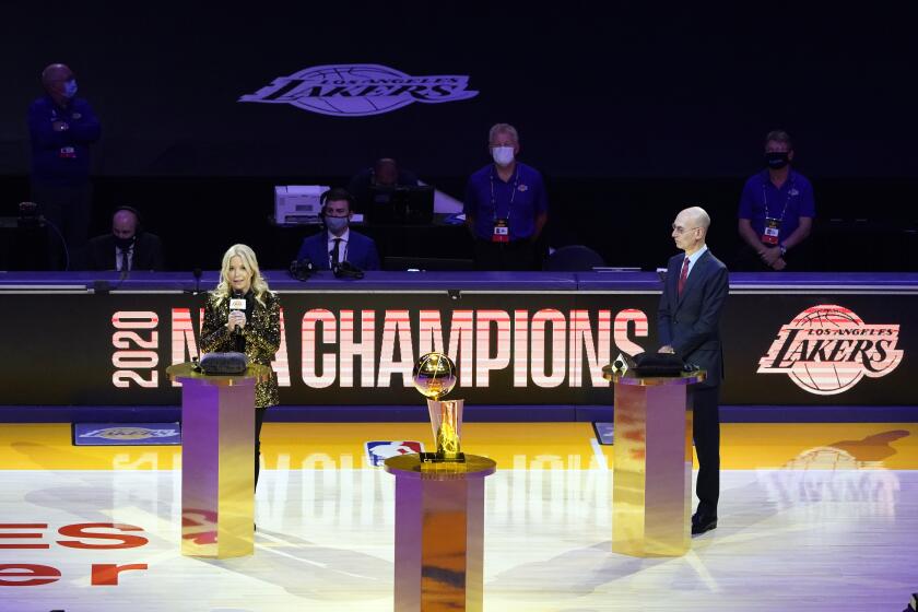 Los Angeles Lakers owner Jeanie Buss, left, speaks behind the championship trophy, near NBA Commissioner Adam Silver before the team's basketball game against the Los Angeles Clippers on Tuesday, Dec. 22, 2020, in Los Angeles. (AP Photo/Marcio Jose Sanchez)