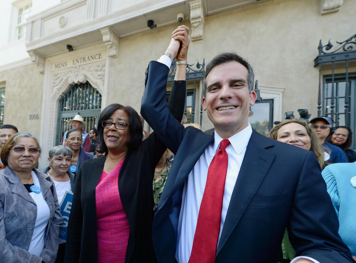Mayoral candidate Eric Garcetti holds up the arm of one-time mayoral candidate Jan Perry after she threw her support behind him in the Los Angeles mayoral race.