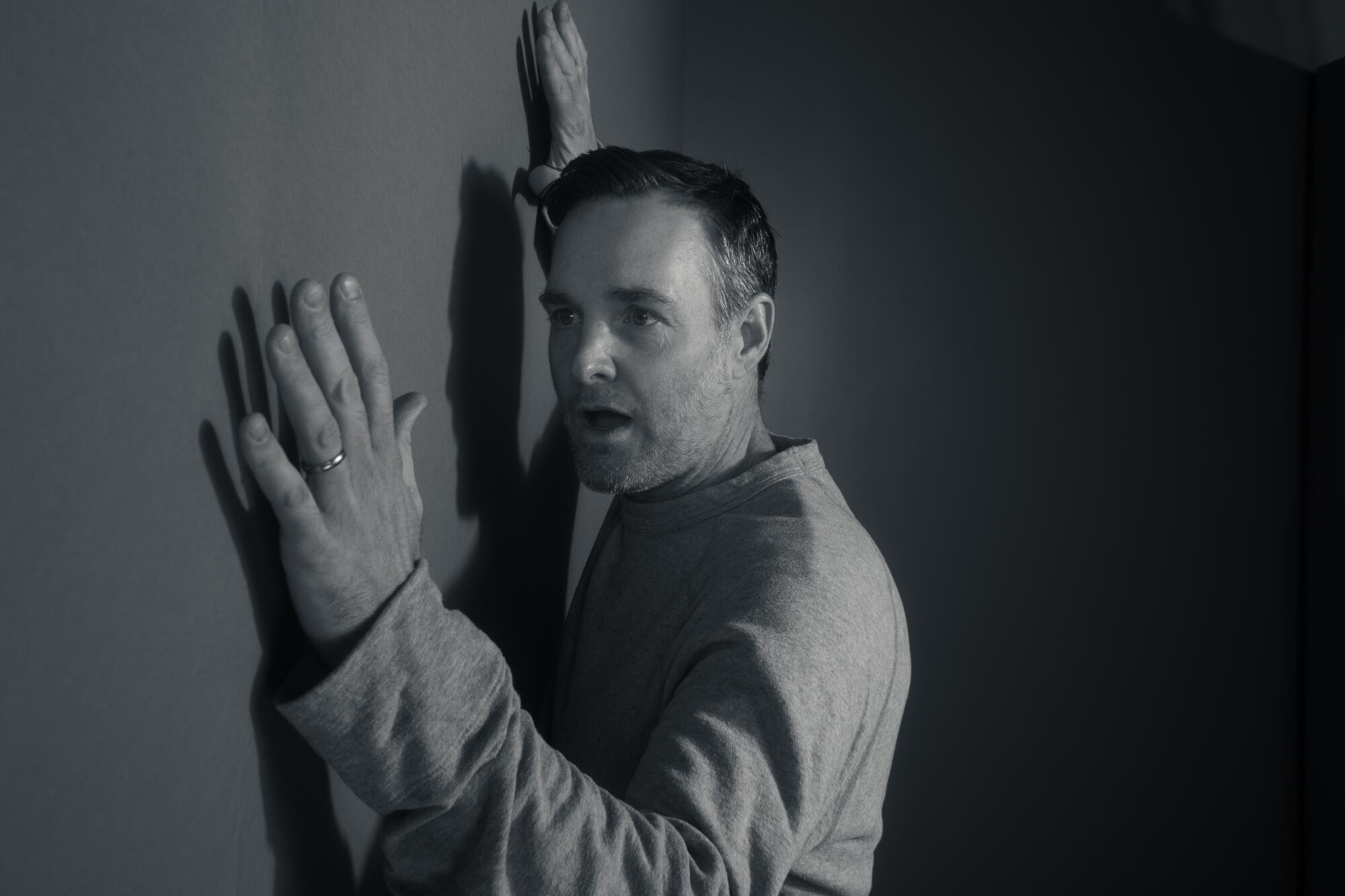 Will Forte holds his hands up to a wall.