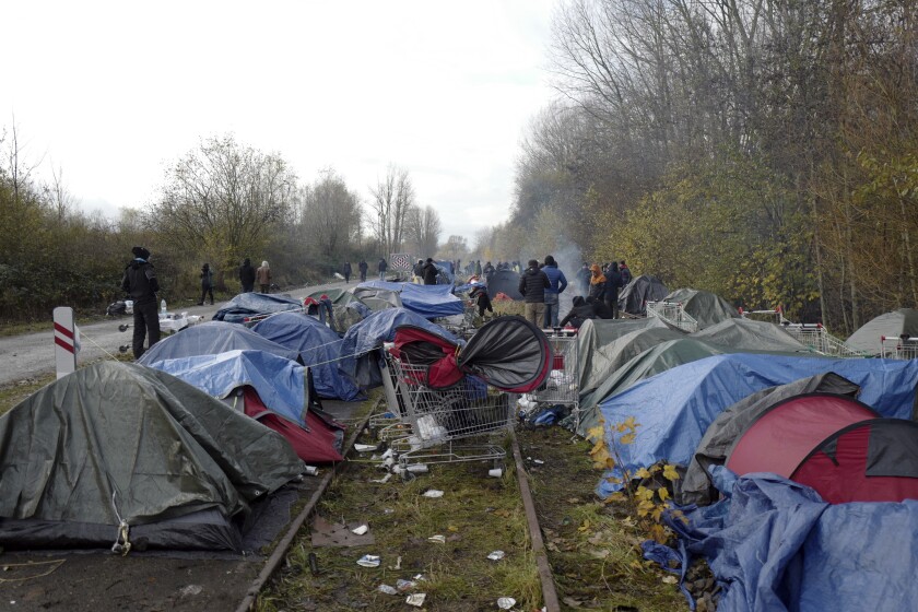 Migrants at a makeshift camp of tents along rail tracks