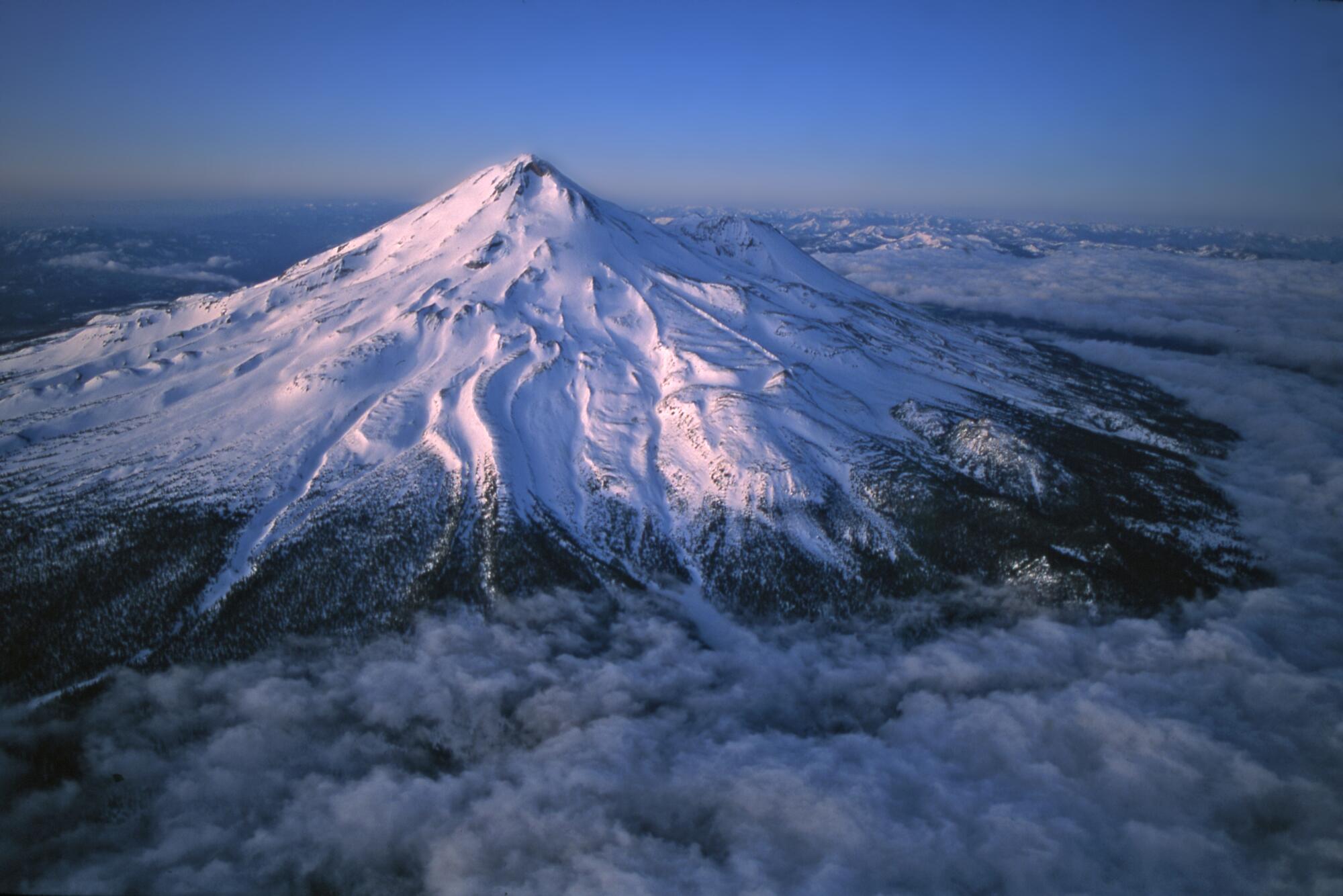 A snow-covered, conical mountain peak