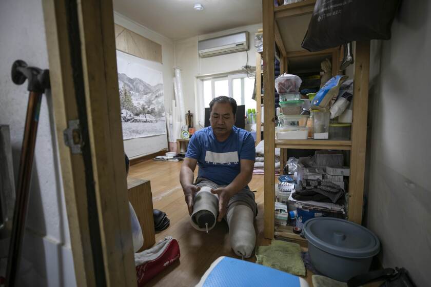 Mr. Yoon Yong-ju, representative of the neighborhood community center in Jjokbangchon in Dongja-dong, prepares to put on the prosthetic legs in his room. Jjokbangchon means a neighborhood with a high density of jjokbangs, cramped single-person occupancies that were illegally subdivided in the past. The residents of Jjokbangchon welcome the government's public housing project; however, many landlords oppose to the idea.
