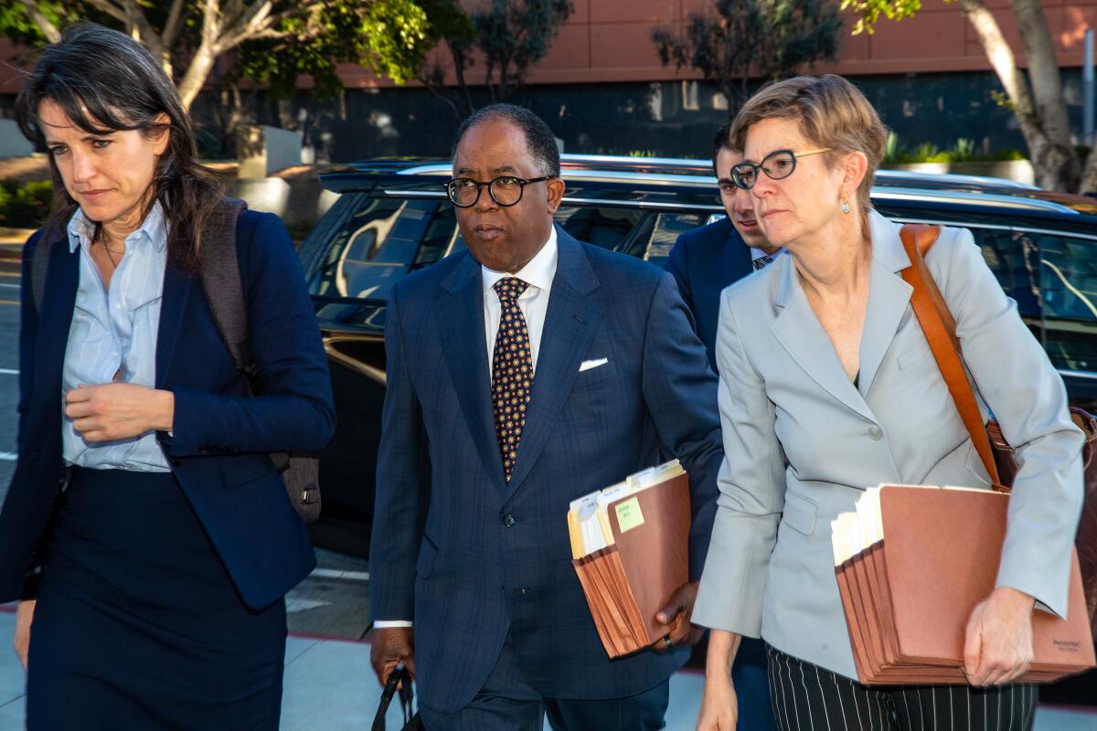 Mark Ridley-Thomas is flanked by two female attorneys.