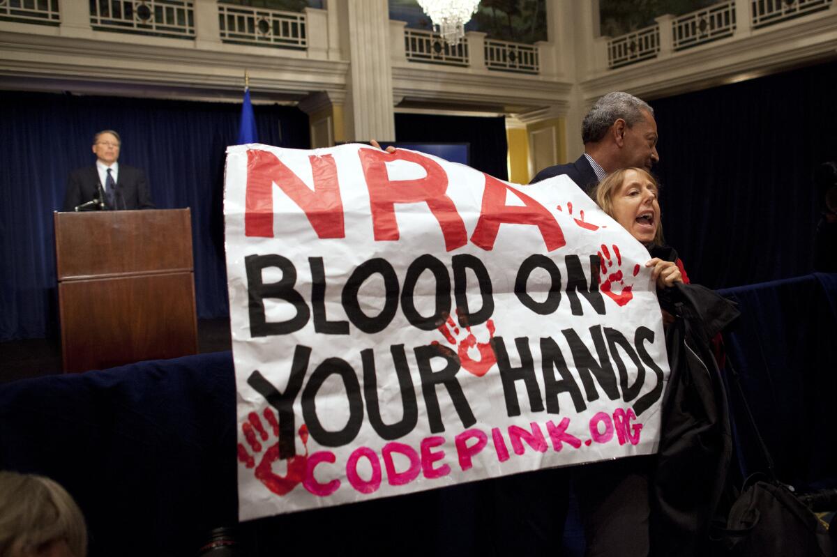 A Code Pink activist is led away by security as she protests during a statement by NRA executive vice president Wayne LaPierre in 2012.