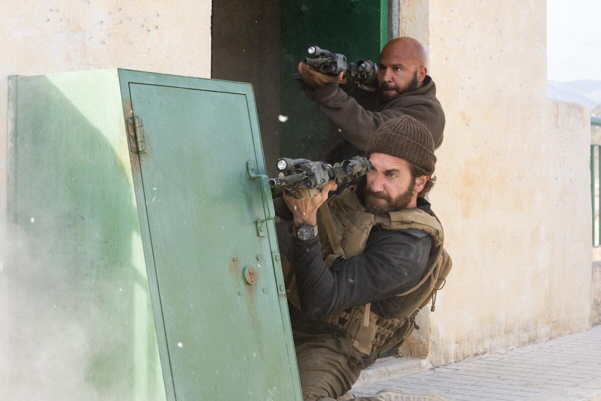 two men shooting guns from inside a doorway 