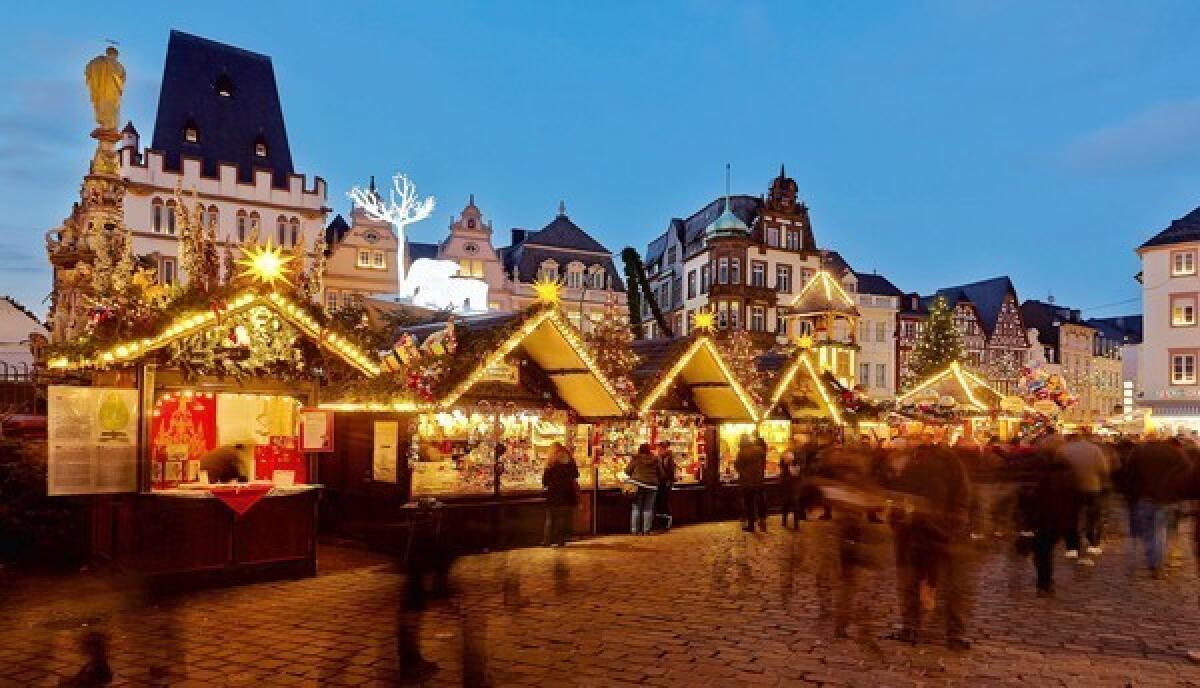 Visitors walk past illuminated stands of a Christmas market at the Hauptmarkt in Trier, western Germany.