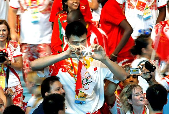 Chinese basketball star Yao Ming snaps a photo of fellow athletes during the closing ceremony.