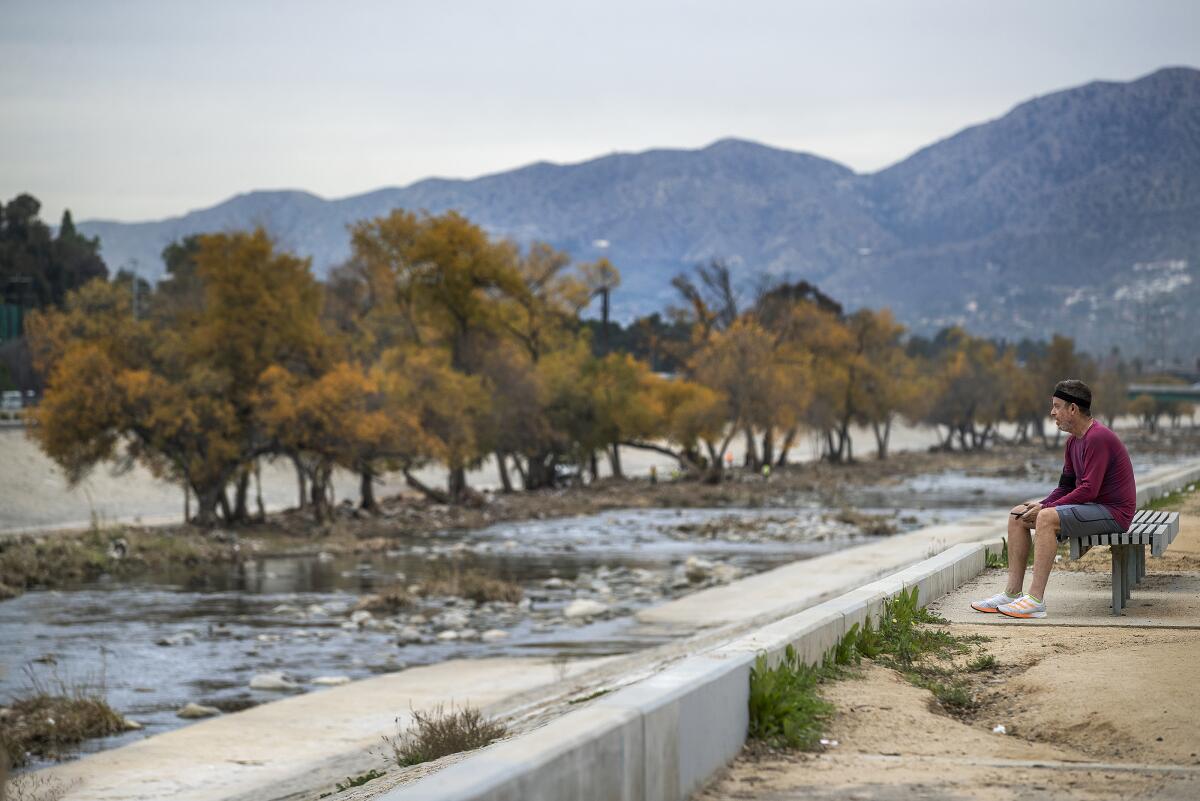 A man sits by the Los Angeles River.
