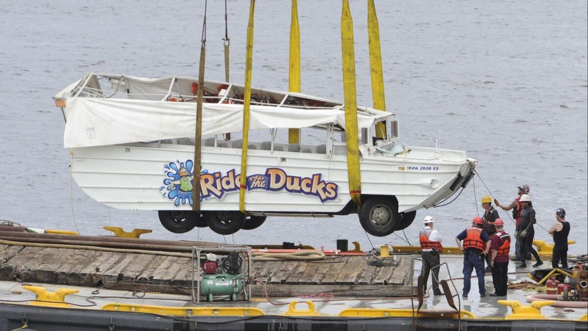 The duck boat that was involved in a mid-river collision with a barge on July 7, 2010, dangles above a salvage barge after being hoisted out of the Delaware River in Philadelphia.