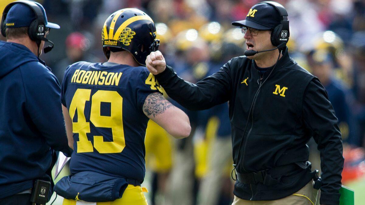 Michigan coach Jim Harbaugh, right, congratulates long snapper Andrew Robinson (49) after a Michigan touchdown in the first quarter against Ohio State on Nov. 25.