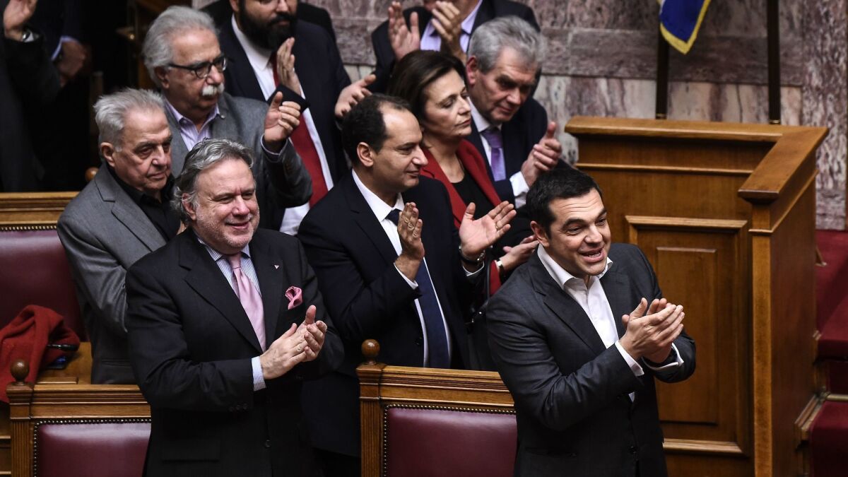 Greece's Prime Minister Alexis Tsipras, right, and Alternate Minister of Foreign Affairs Georgios Katrougalos, left, celebrate following a voting session at the Greek Parliament, in Athens, on Friday.