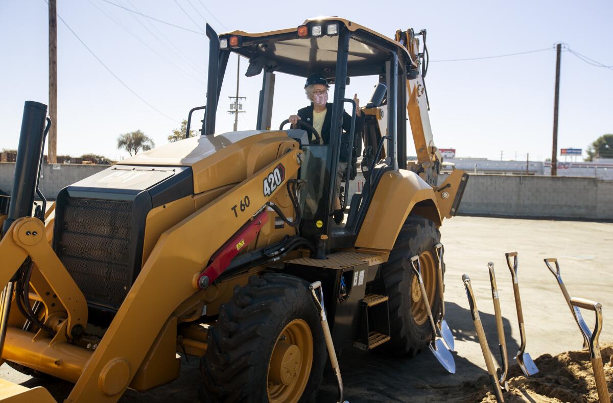 Fountain Valley Mayor Cheryl Brothers gives a thumbs-up from inside the cab of a backhoe.