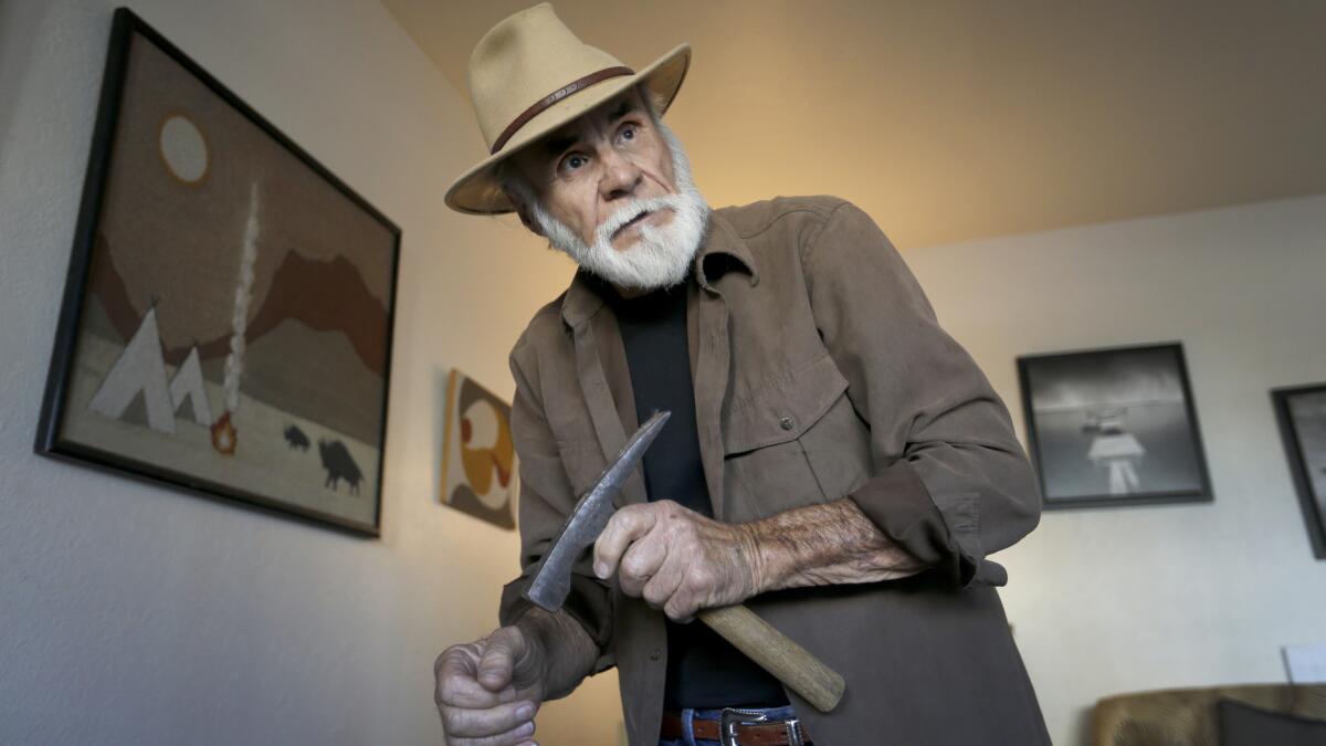 Field paleontologist Richard Cerutti, shown in his Imperial Beach apartment, holds a brick hammer that he uses to help loosen hardened sediment at some excavations.