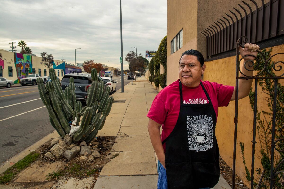 Eddi Ortiz, wearing an apron, stands outside of his business