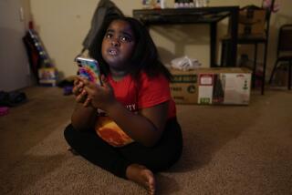Brooklynn Chiles, 8, glances up from her smart phone at home where she lives with her mother, Danielle Chiles in Washington, Sunday, Jan. 9, 2022. Brooklynn lost her father to COVID-19 last year and has tested positive three times herself. She is part of a NIH-funded multi-year study at Children's National Hospital to look at impacts of COVID-19 on children's physical health and quality of life. (AP Photo/Carolyn Kaster)