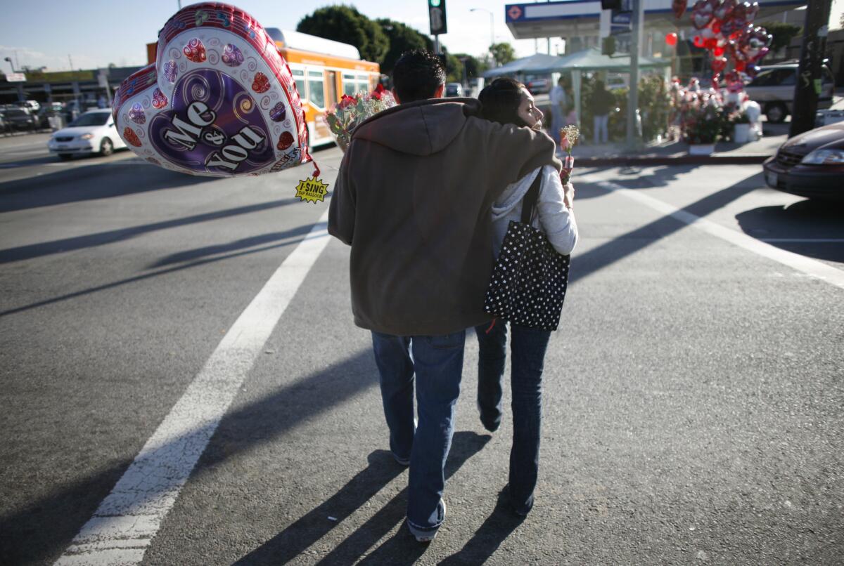 A couple cross 4th Street in Boyle Heights after purchasing balloons for Valentine's Day.