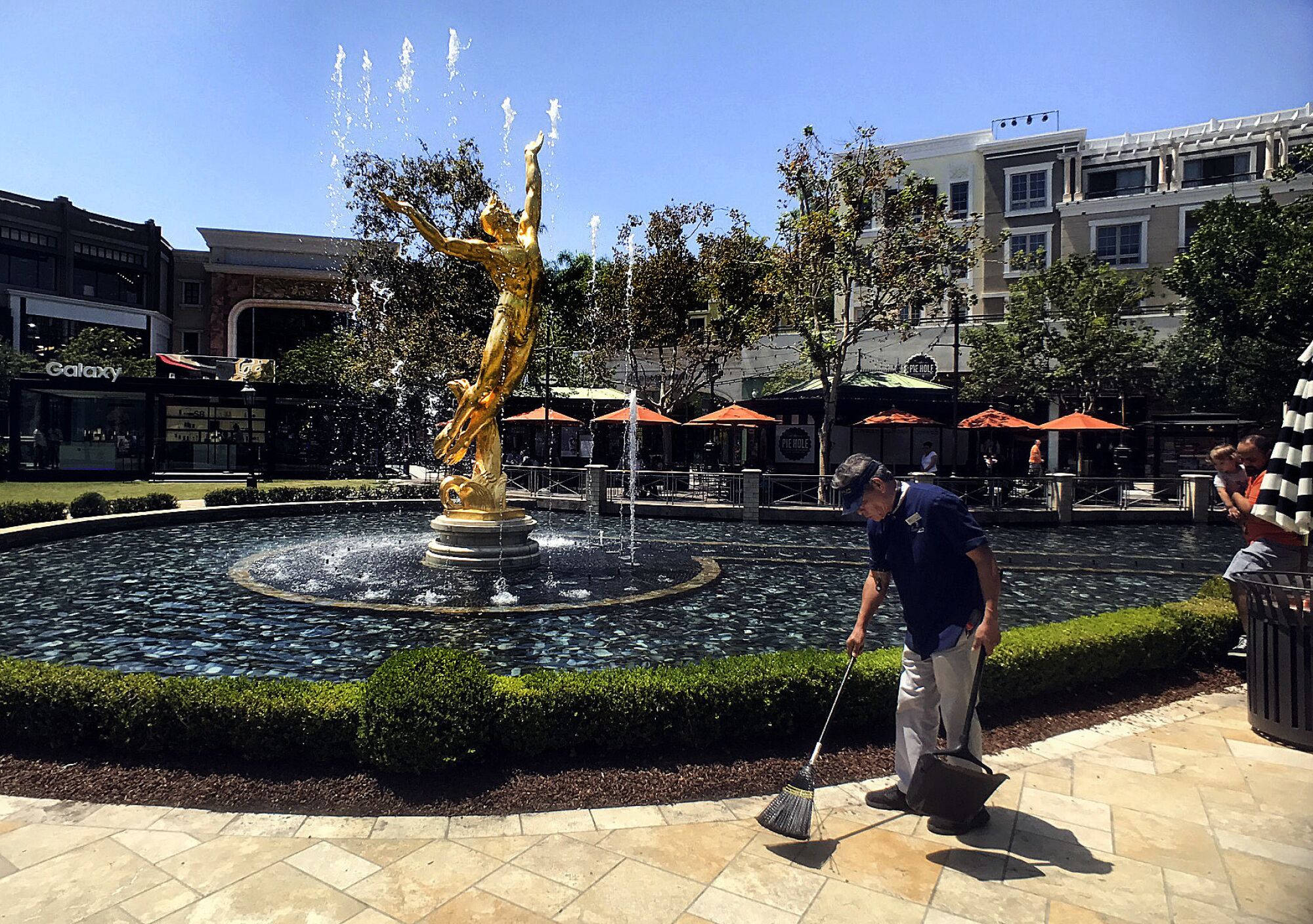 A man sweeps by an outdoor fountain