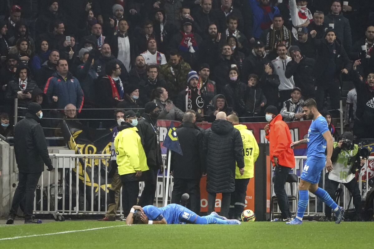 Marseille's Dimitri Payet reacts after being injured by an object thrown by a Lyon's supporter during the French League One soccer match between Lyon and Marseille, in Decines, near Lyon, central France, Sunday, Nov. 21, 2021. (AP Photo/Laurent Cipriani)