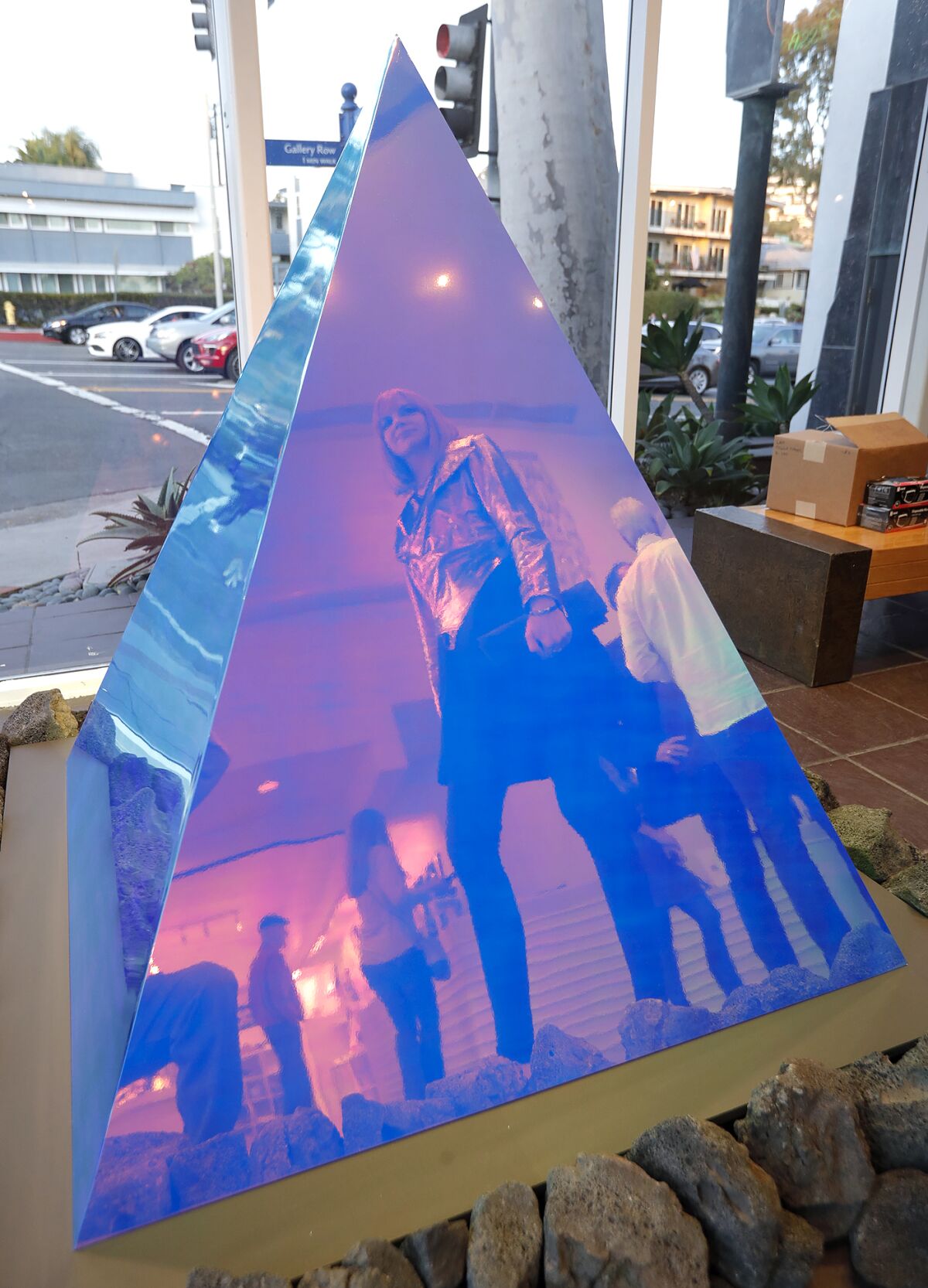 Artist Kelly Berg is reflected in her exhibit, "Pyramidion," in the lobby of the Laguna Art Museum.
