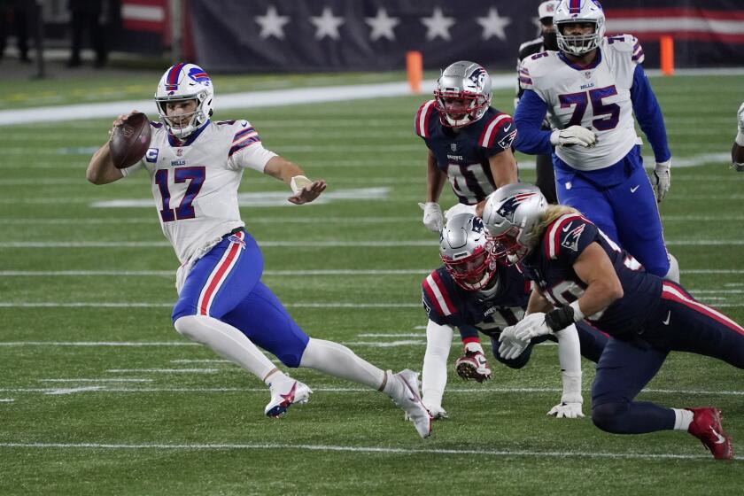 Buffalo Bills quarterback Josh Allen, left, scrambles against the New England Patriots in the first half of an NFL football game, Monday, Dec. 28, 2020, in Foxborough, Mass. (AP Photo/Charles Krupa)