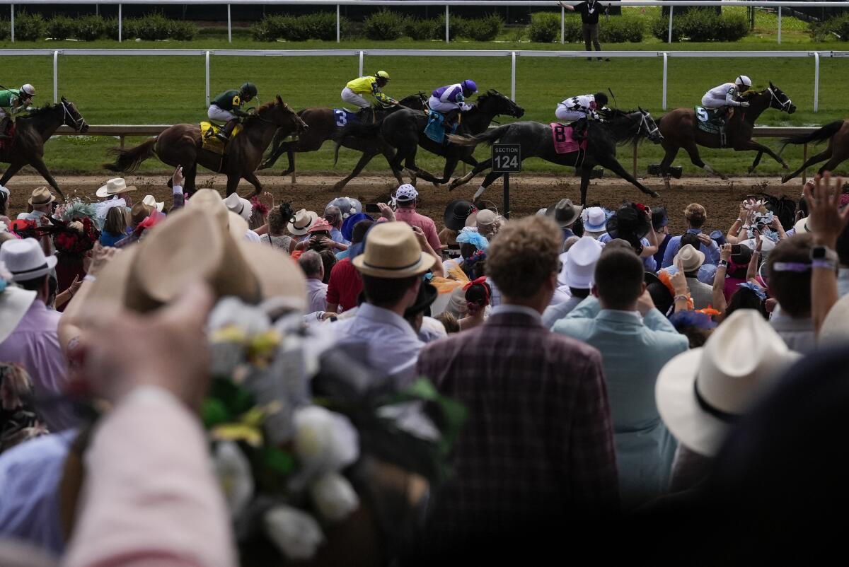 Fans with ornate hats as horses run during an early race at Churchill Downs Saturday in Louisville, Ky. 