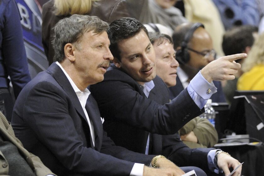 Stan Kroenke and his son, Josh, talk on the sideline while watching the Nuggets play