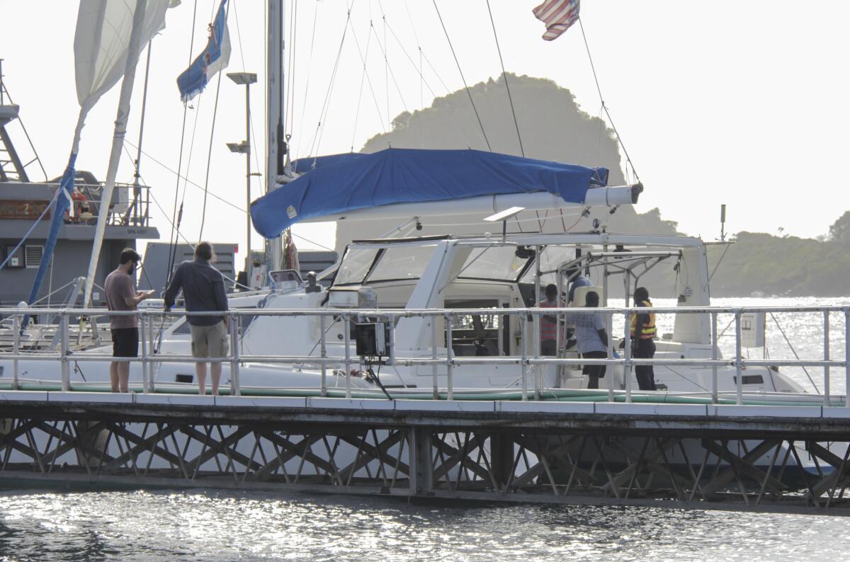 Relatives stand nearby as investigators stand aboard the yacht Simplicity in St. Vincent