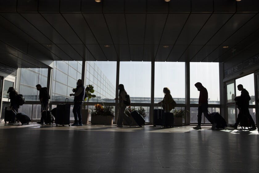 Silhouette of travelers at an airport next to windows