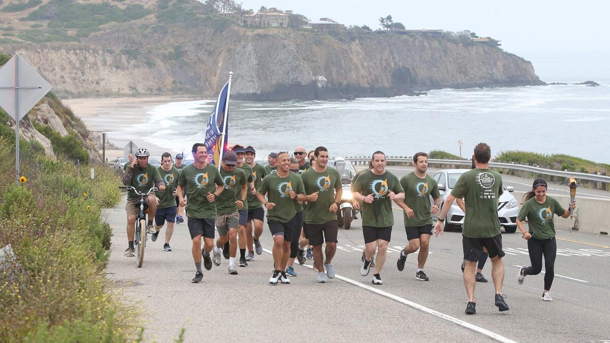 Laguna Beach police officers and lifeguards run up Coast Highway past Crystal Cove on Thursday in the annual Law Enforcement Torch Run for Special Olympics Southern California. Newport Beach police later carried the torch to Mariners Park.