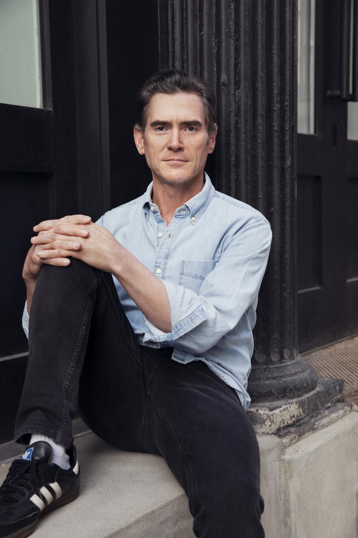  Billy Crudup sits on a ledge outside for a portrait.