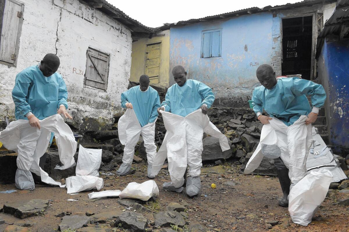 Staffers with the International Committee of the Red Cross don protective suits before collecting the body of an Ebola victim in Monrovia, Liberia.