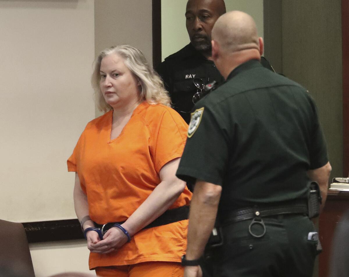 Tammy Sytch is clad in an orange jail jumpsuit and handcuffs and escorted by two male deputies inside a courtroom