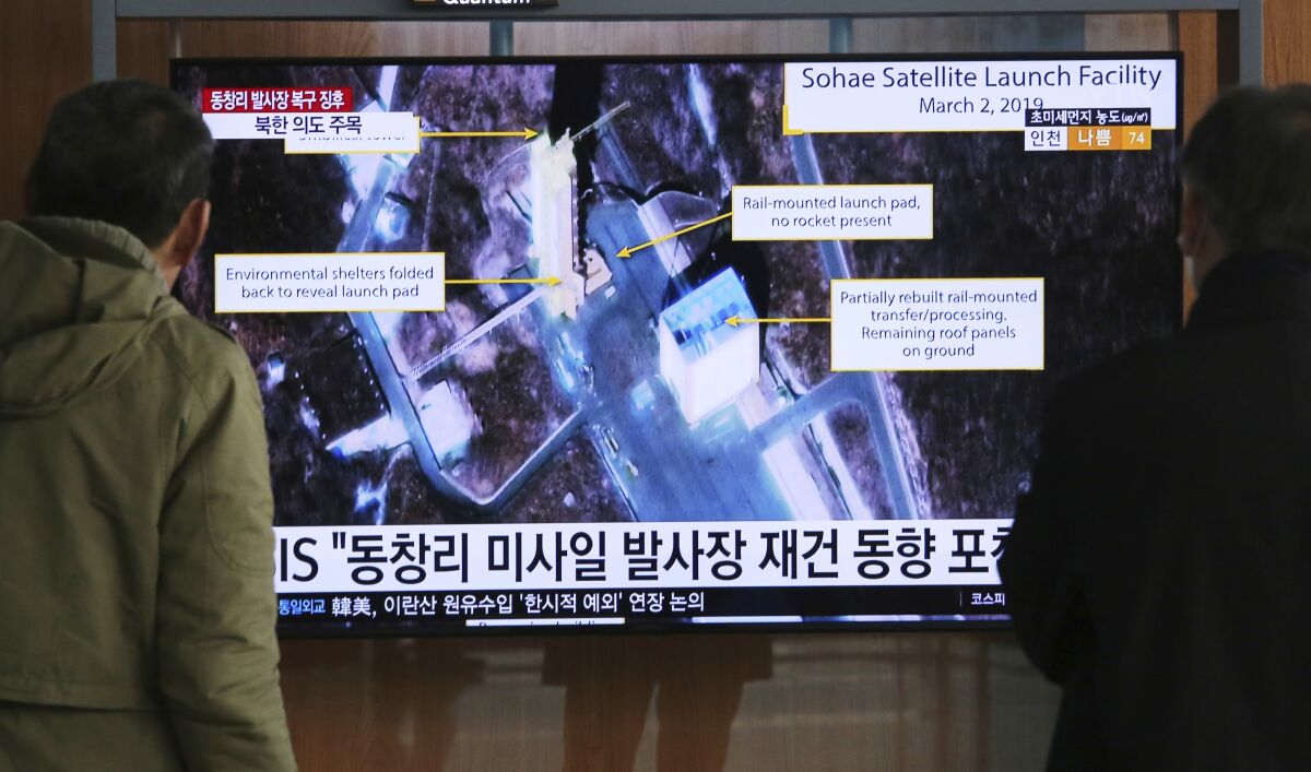 People in Seoul watch a TV screen showing an image of a North Korean rocket launch station.
