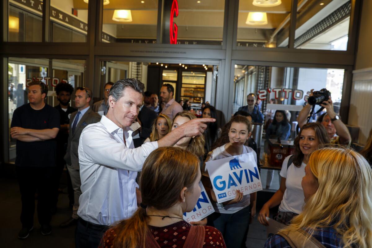 Gavin Newsom talks to young people holding campaign signs.