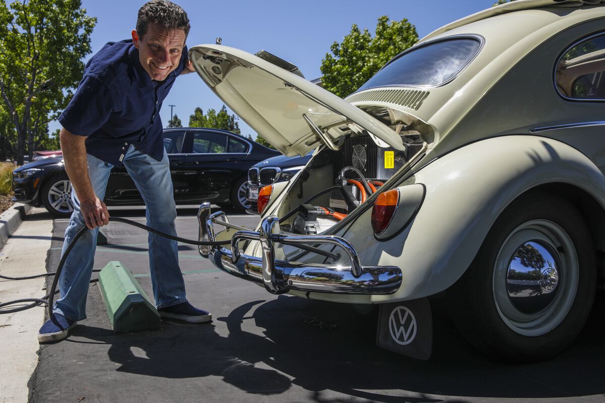 Mark Wagner, who converted his 1962 VW Beetle ragtop from gas to electric, plugs in at a charging station in Irvine.