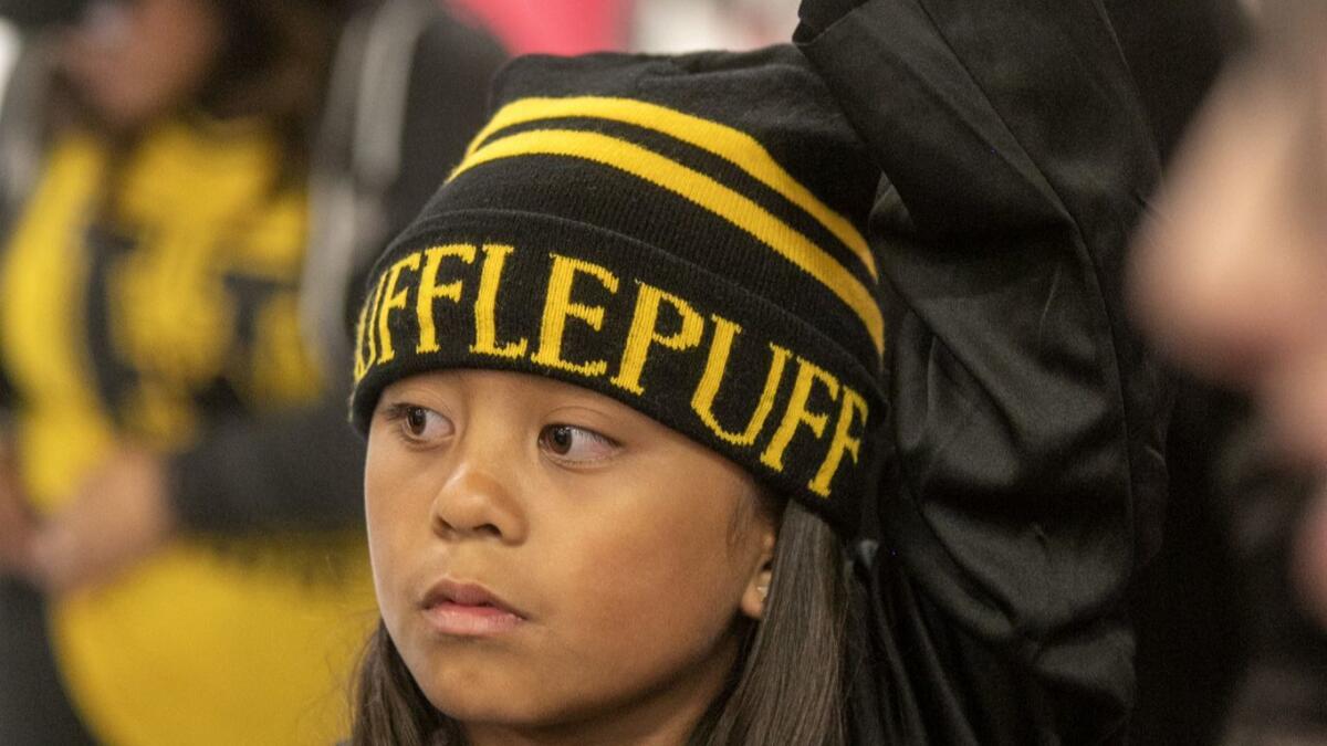 In a Hufflepuff cap, Chole Linsangan raises her hand to answer a Harry Potter Jeopardy trivia question.