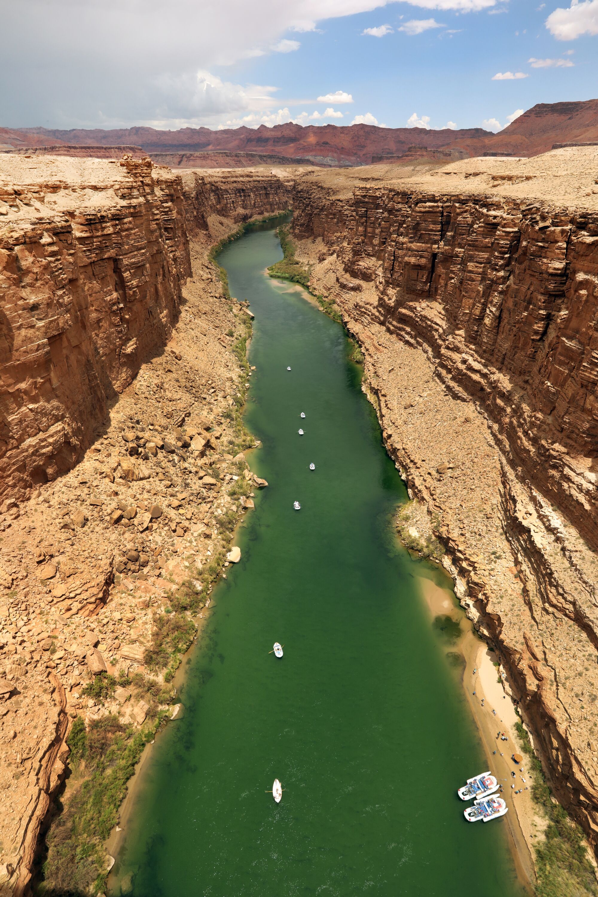 Rafters float down a river as seen between a canyon from above
