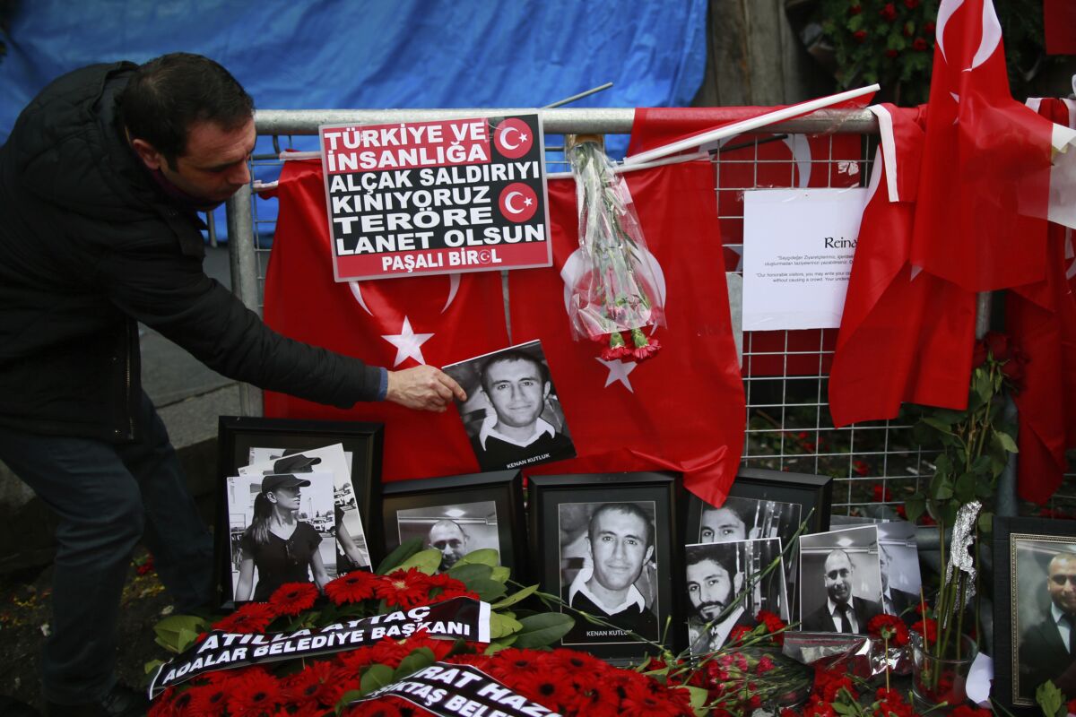 FILE - In this Wednesday, Jan. 4, 2017 file photo, a man adjusts a victim's photograph displayed with floral tributes and Turkish flags, outside the Reina night club following the New Year's day attack, in Istanbul. A Turkish court has on Monday, Sep. 7, 2020 sentenced an Islamic State militant to life in prison over the New Year’s Eve attack on a nightclub in Istanbul that left 39 people dead in 2017. Albulkadir Masharipov of Uzbekistan was charged with membership in a terror group, murder and attempting to overthrow the constitutional order, among other charges. (AP Photo/Emrah Gurel, file)