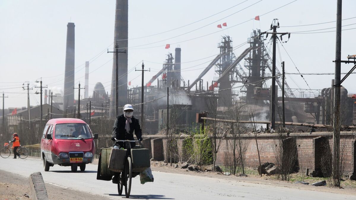 A cyclist wearing a protective face mask while riding in 2011 along a dusty road, where dozens of factories process rare earths, near Baotou in Inner Mongolia.